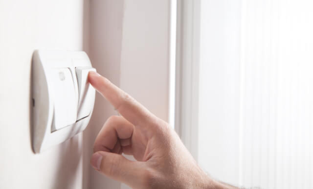 Doigt appuyant sur un interrupteur de volet roulant